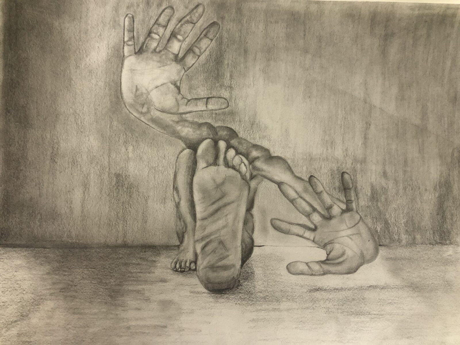 A graphite drawing of two open hands and the sole of a foot, joined by a long twisting arm, set against a shaded wall and floor.